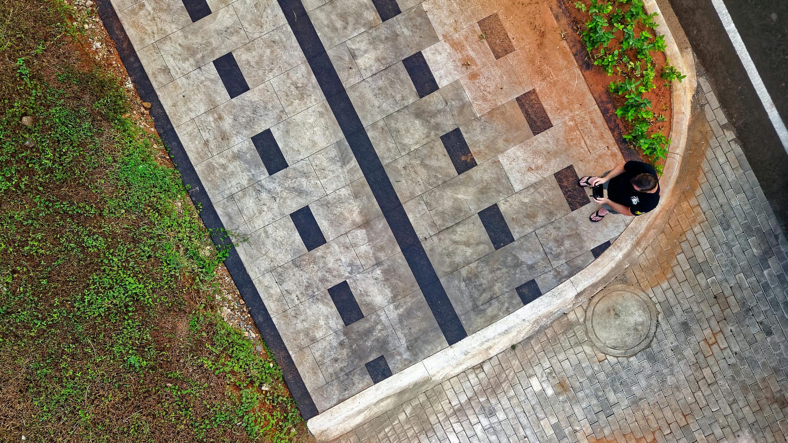 Aerial shot capturing a modern pavement design and greenery with a person walking.