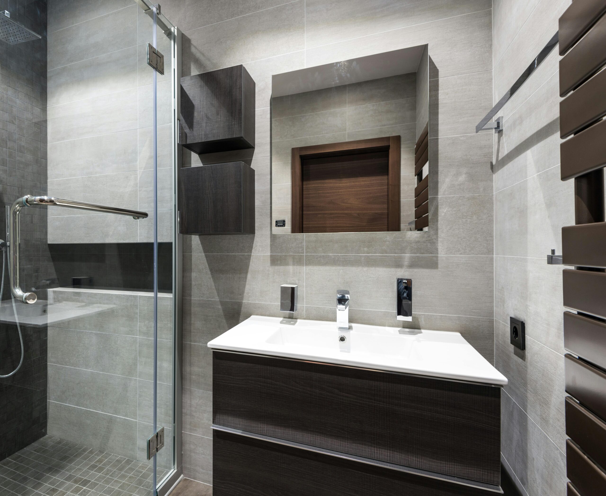 Stylish modern bathroom featuring dark wood elements, sleek sink, and glass shower.